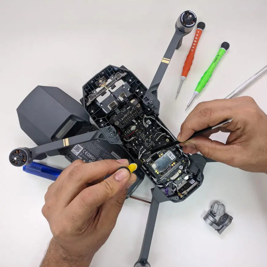 Tecnico al lavoro su un drone aperto, con strumenti per la riparazione